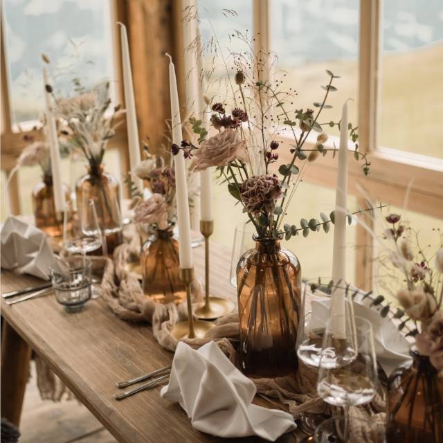 liebevoll dekorierter Hochzeitstisch mit Blumengestecken